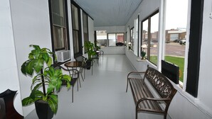 A covered outdoor seating area with tables and chairs, potted plants, and a bench with a 'WELCOME' sign. - Perfect Stay Inn & Suites (Blair)