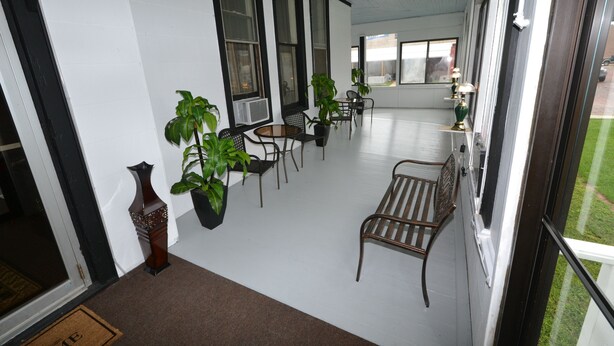 A covered outdoor seating area with potted plants, a bench, and a table. - Perfect Stay Inn & Suites (Blair)