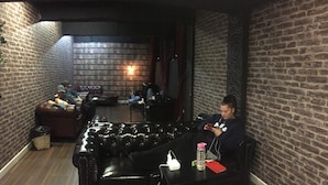 A cozy lounge area with leather sofas, a coffee table, and brick walls. - Europa Melbourne - Hostel (Melbourne)