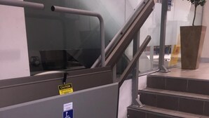 A staircase with a handrail, a caution sign, and a disabled access sign. - Europa Melbourne - Hostel (Melbourne)