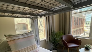 A hotel room with a bed, a chair, a small table, and a potted plant. - Europa Melbourne - Hostel (Melbourne)
