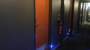 A hallway with a door labeled '110' and a fire extinguisher mounted on the wall. - Europa Melbourne - Hostel (Melbourne)