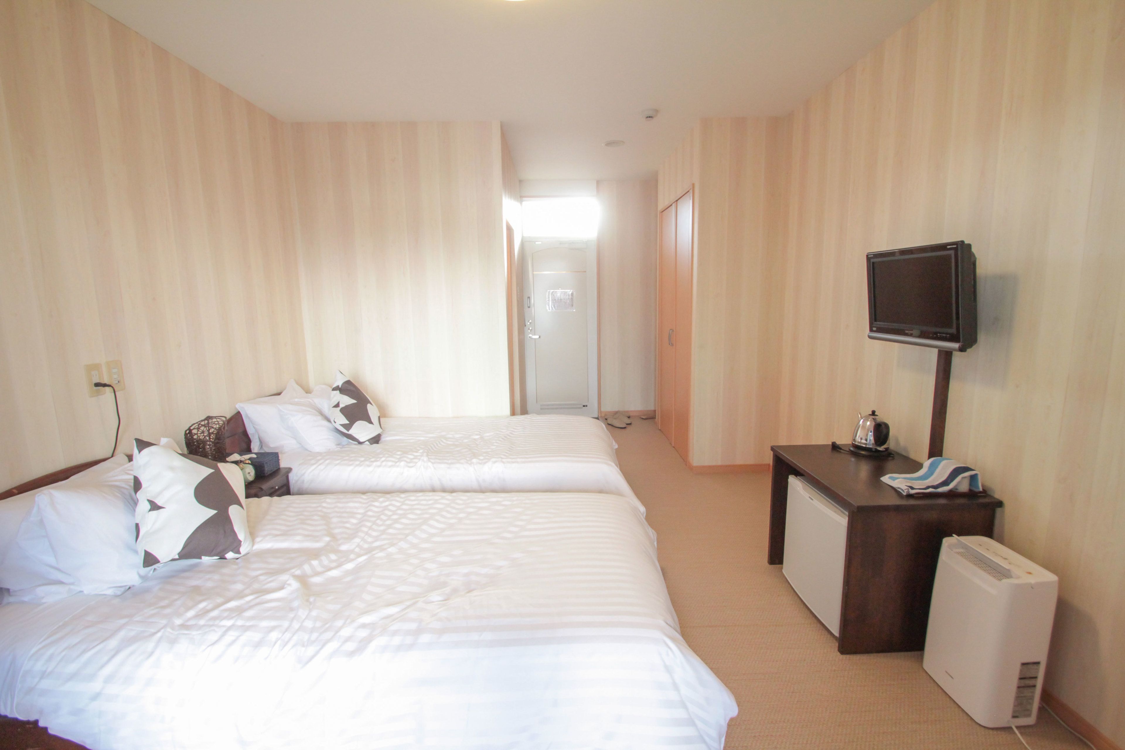 Een hotelkamer met twee bedden, een bureau, een televisie en een radiator.