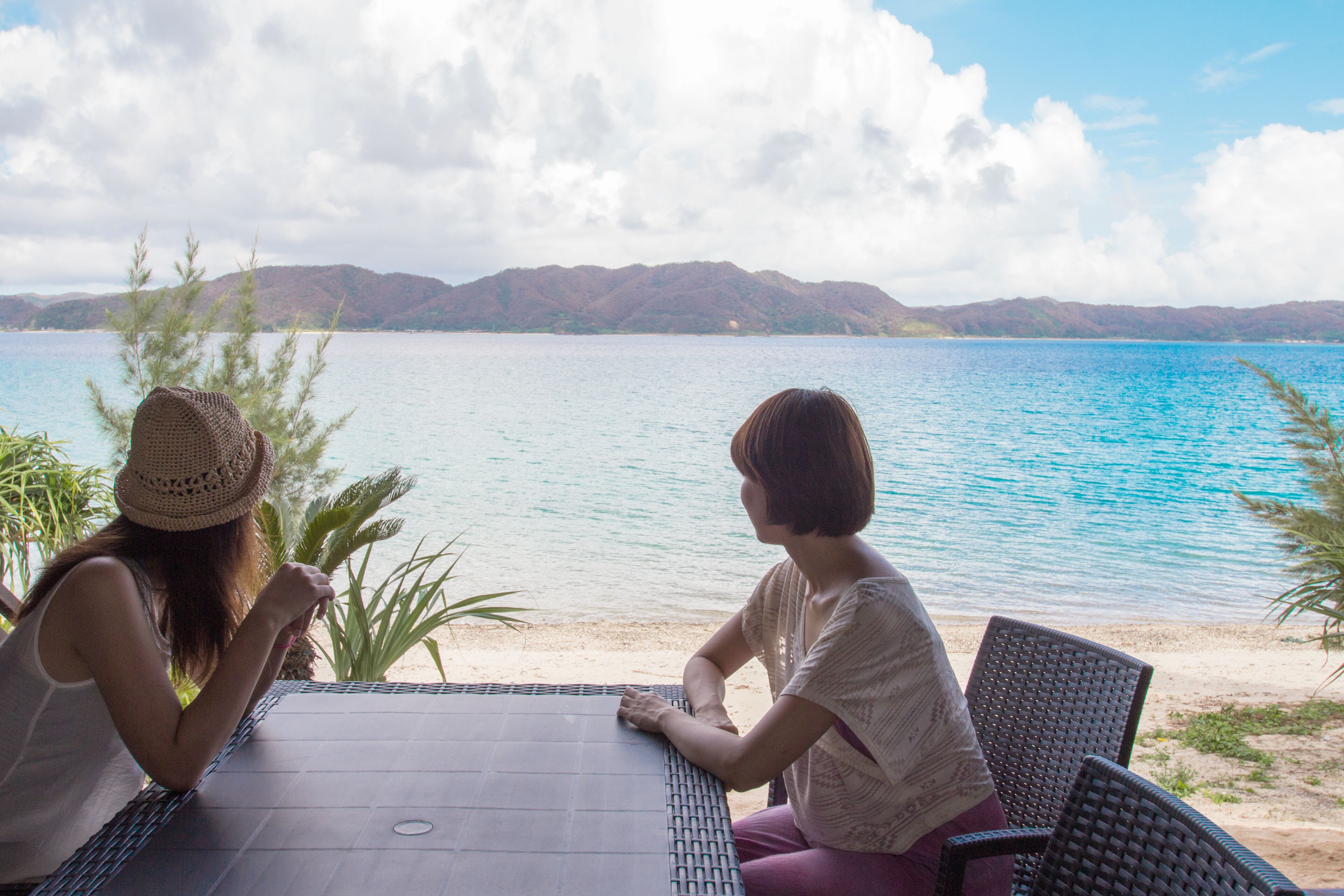 Two people sitting at a table with a view of a lake and mountains in the background.