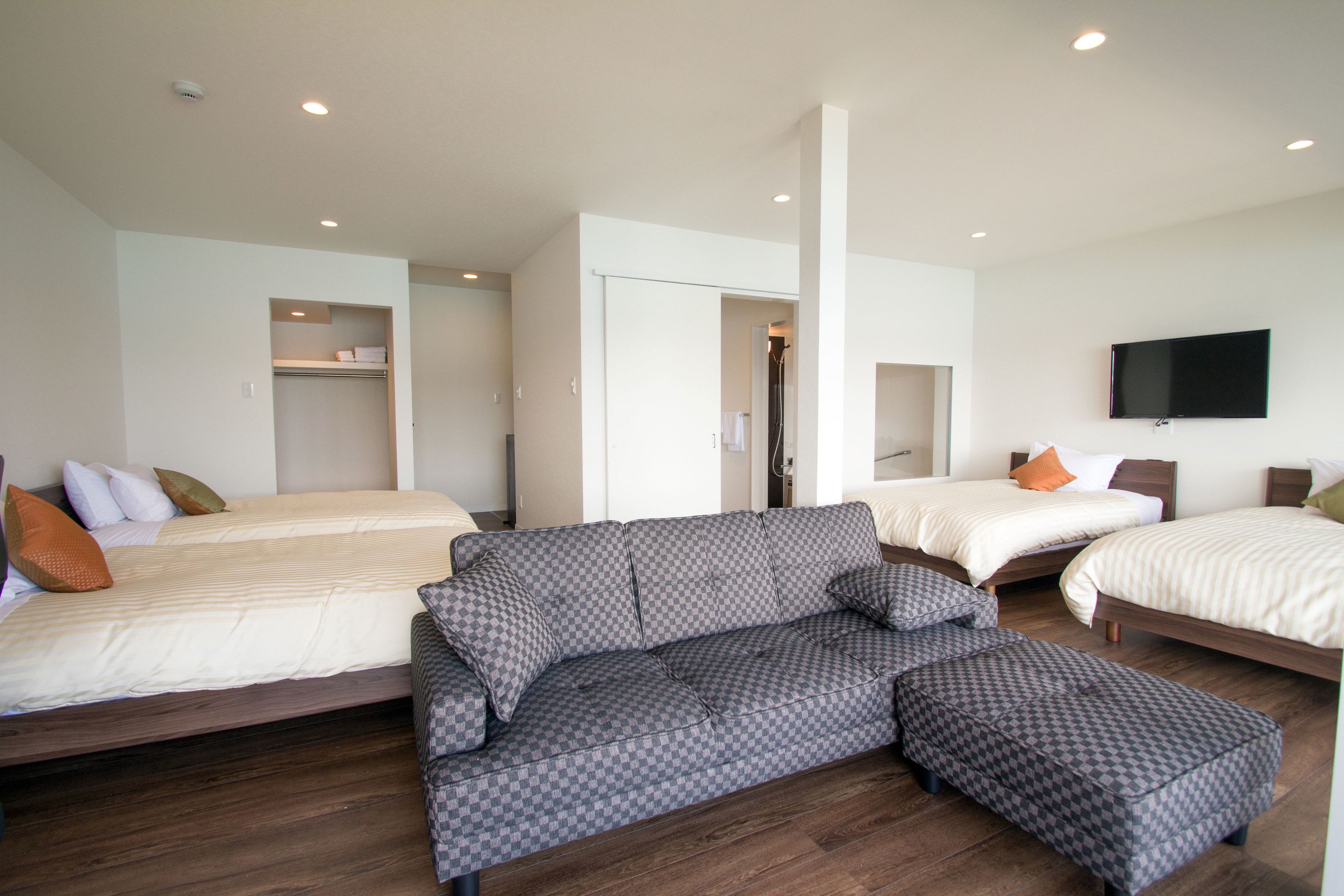Une chambre d’hôtel avec trois lits, un canapé et une télévision.