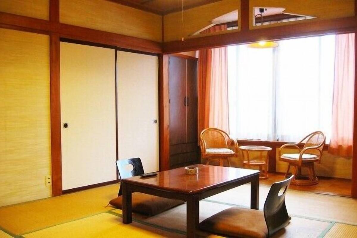A traditional Japanese room with tatami flooring, a low table with cushions, and a sliding door.