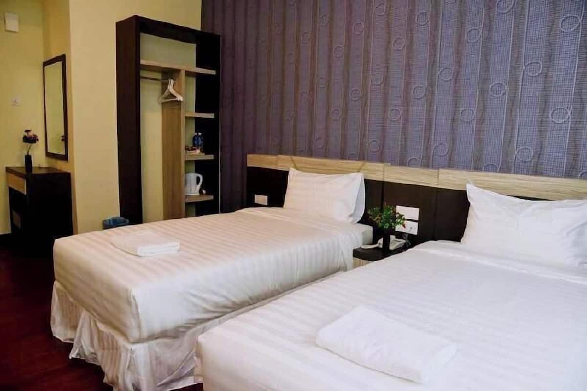 A hotel room with two beds, a wardrobe, a desk with a chair, and a mirror.