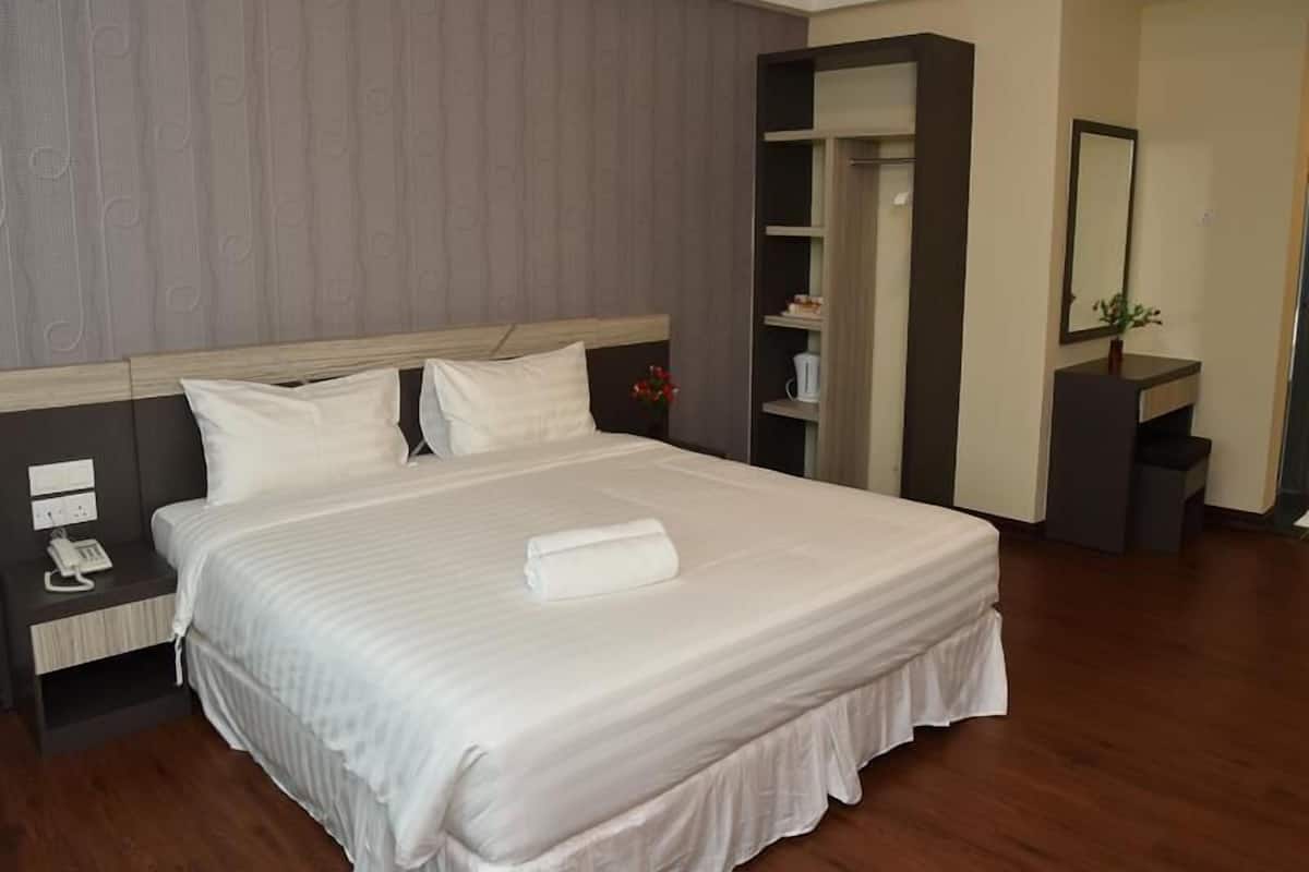 A hotel room with a large bed, a nightstand, a wardrobe, and a mirror.