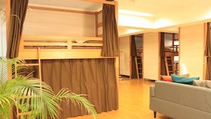 A room with a bunk bed, a sofa, and a potted plant.