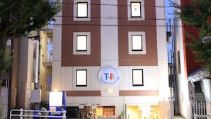 A multi-story building with a distinctive red and white facade, featuring a central logo and multiple windows.