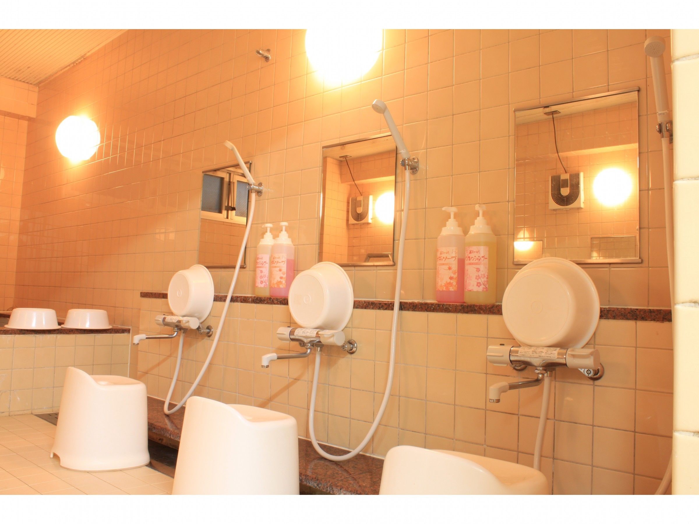 Ein Badezimmer mit mehreren Toiletten, einer Duschkabine und Handtrocknern.