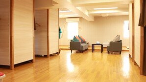 A spacious room with wooden flooring, two grey sofas, a small table, and a sliding door.