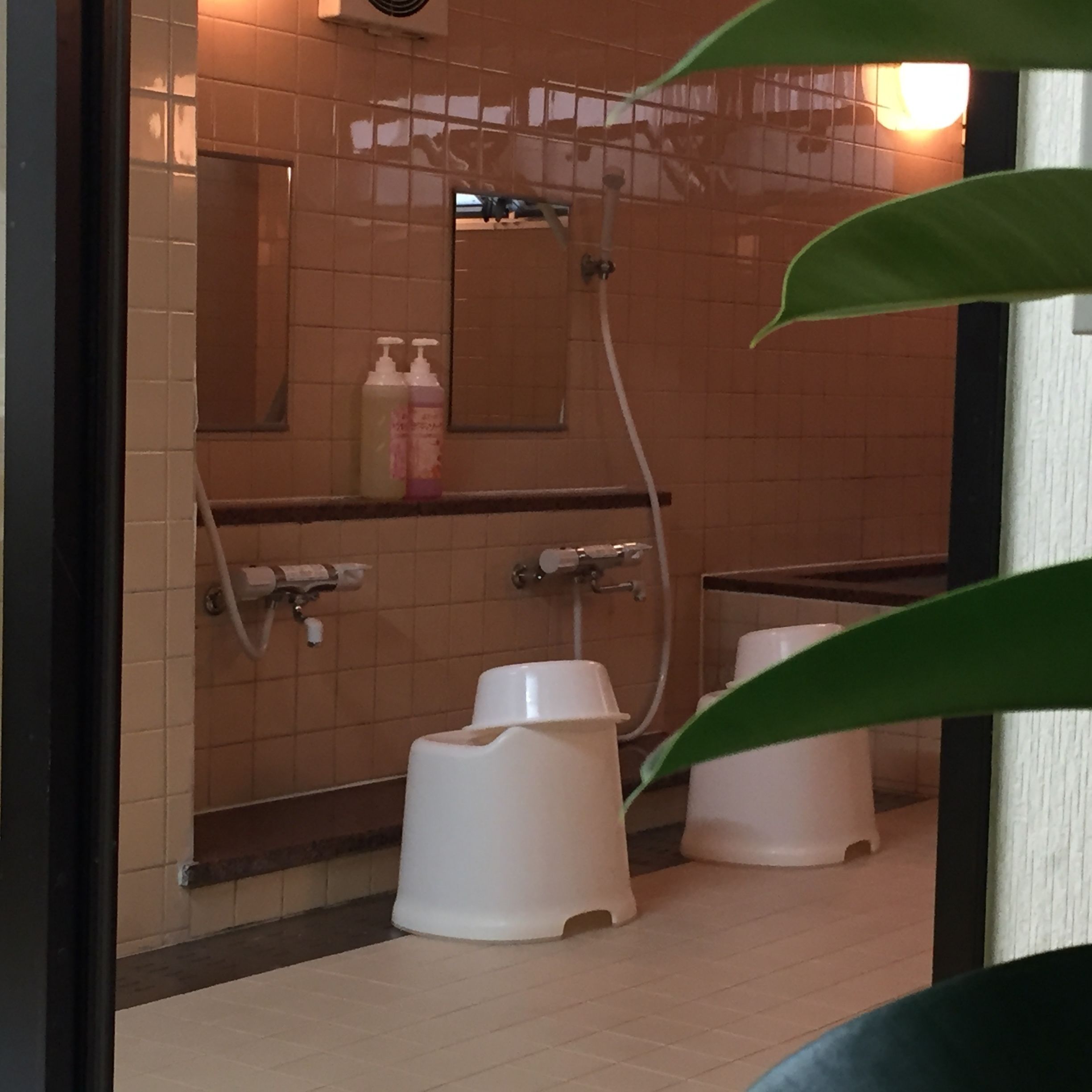 A restroom with two squat toilets, a hand dryer, and a mirror on the wall.