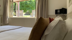 Un dormitorio con una cama grande, una ventana con cortinas, un radiador y un televisor sobre una estantería.
