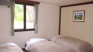 A room with two single beds, a window with curtains, a wall-mounted air conditioner, and a framed picture.