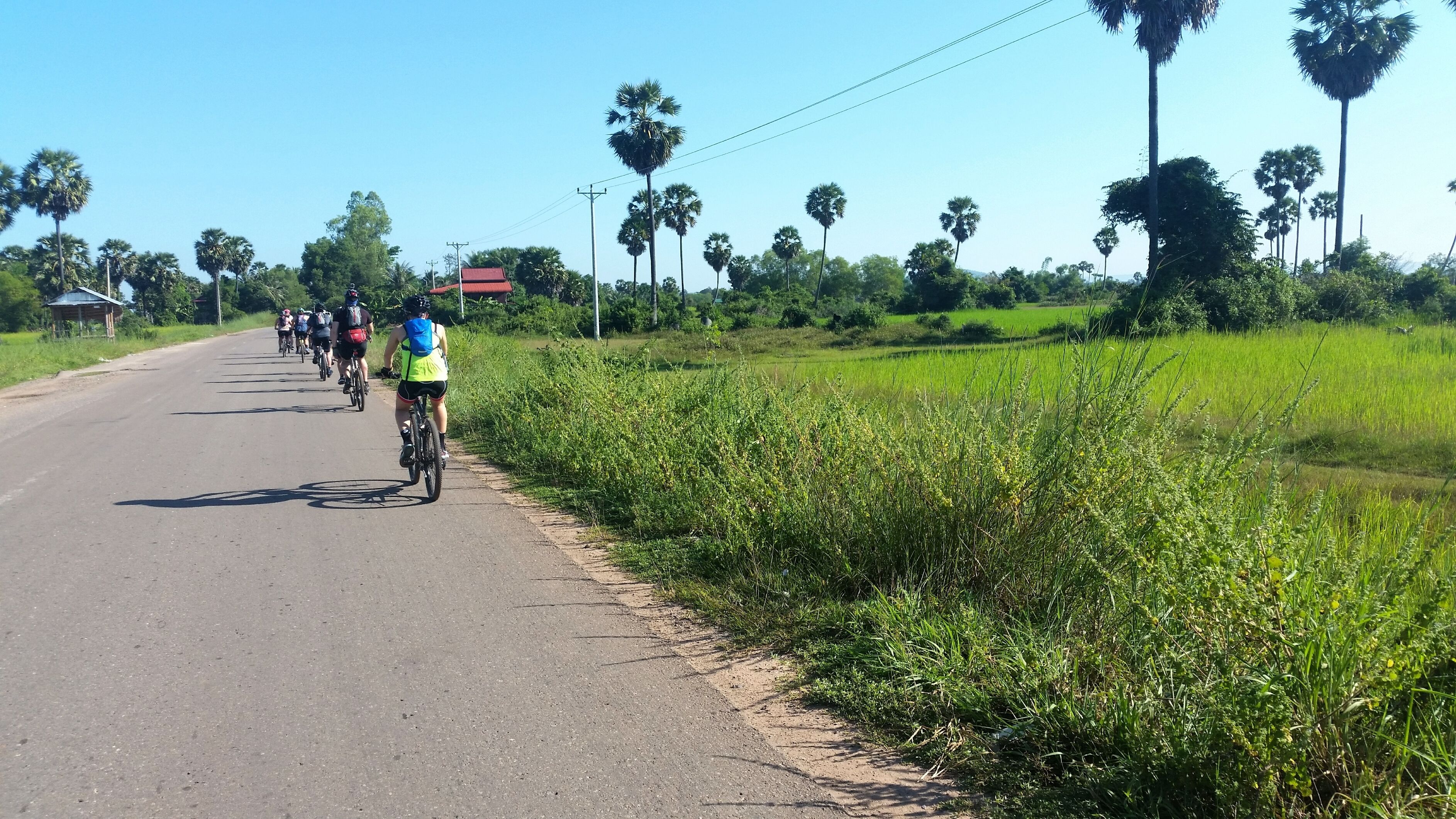 A paved road with cyclists riding alongside.