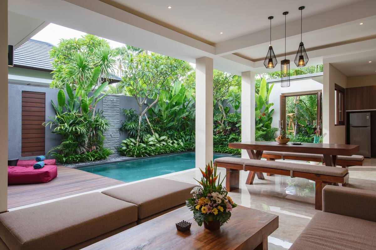 A modern outdoor living area with a pool, seating, and lush greenery.