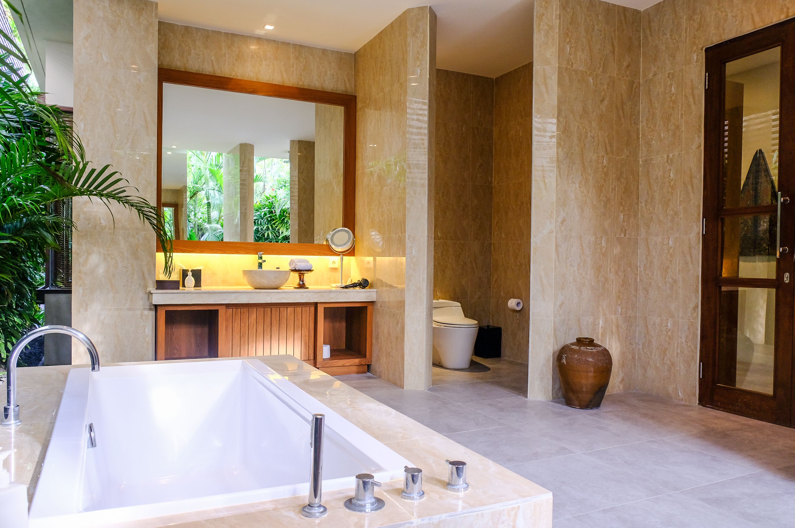A modern bathroom with a large bathtub, a vanity with a mirror, and a toilet.