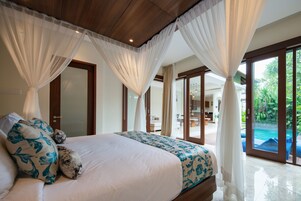 Un dormitorio amplio con una cama grande, cortinas blancas y vistas a una piscina.