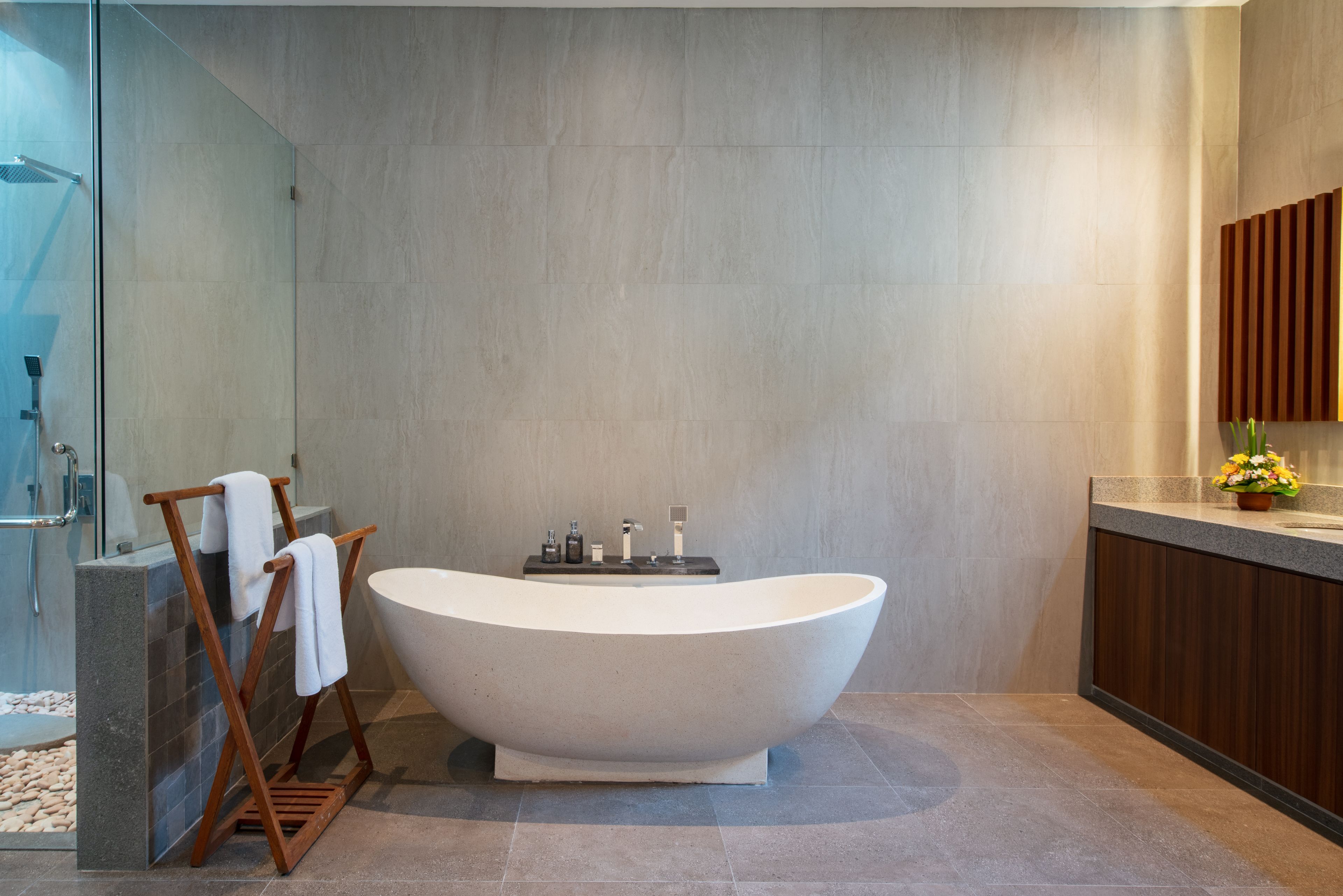 Un baño moderno con una bañera independiente, cabina de ducha con mampara de cristal y un mueble de tocador de madera con lavamanos y espejo.