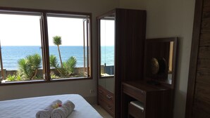Ein Schlafzimmer mit einem Bett, einem Holztisch und einem großen Fenster mit Meerblick.