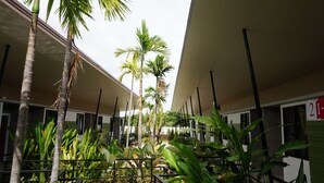 Un patio con palmeras y una piscina, rodeado de habitaciones de hotel.
