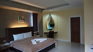 Habitación de hotel con cama, escritorio, silla, televisor y puerta.