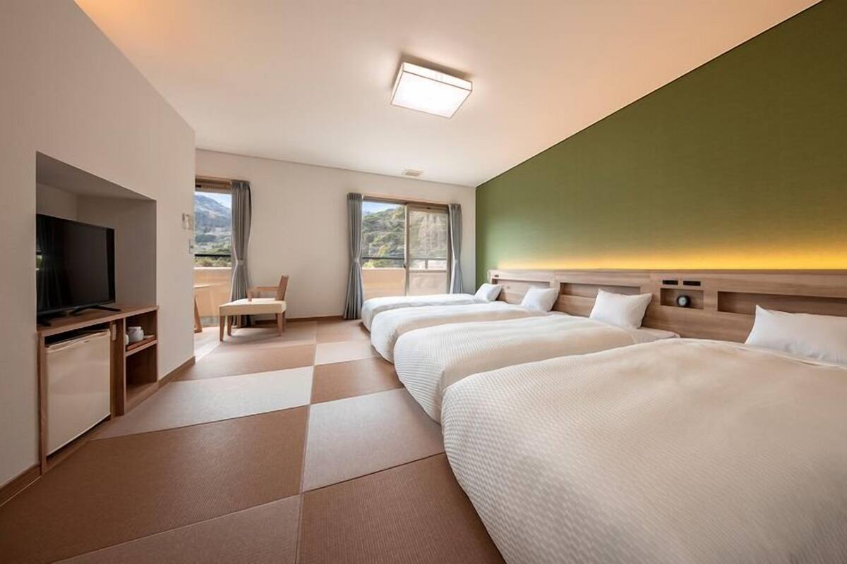 Habitación de hotel con dos camas, un televisor, un escritorio y una silla.