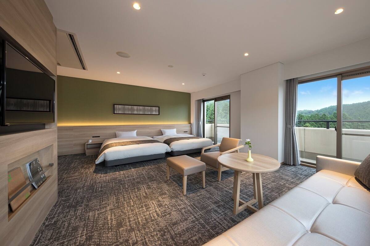 Una habitación de hotel con una cama, un sofá, una mesita y un televisor.