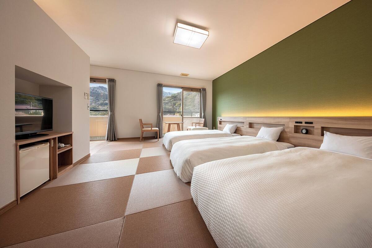Habitación de hotel con dos camas, televisión, escritorio y vistas al exterior.