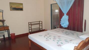 A bedroom with a bed, a desk, a chair, a mirror, and a ceiling fan.
