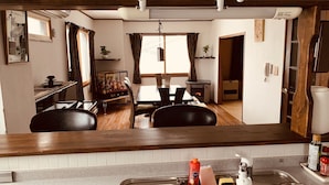 A compact living space with a dining area, kitchen, and a visible living room. - Hakuba Ski Condos (Hakuba)