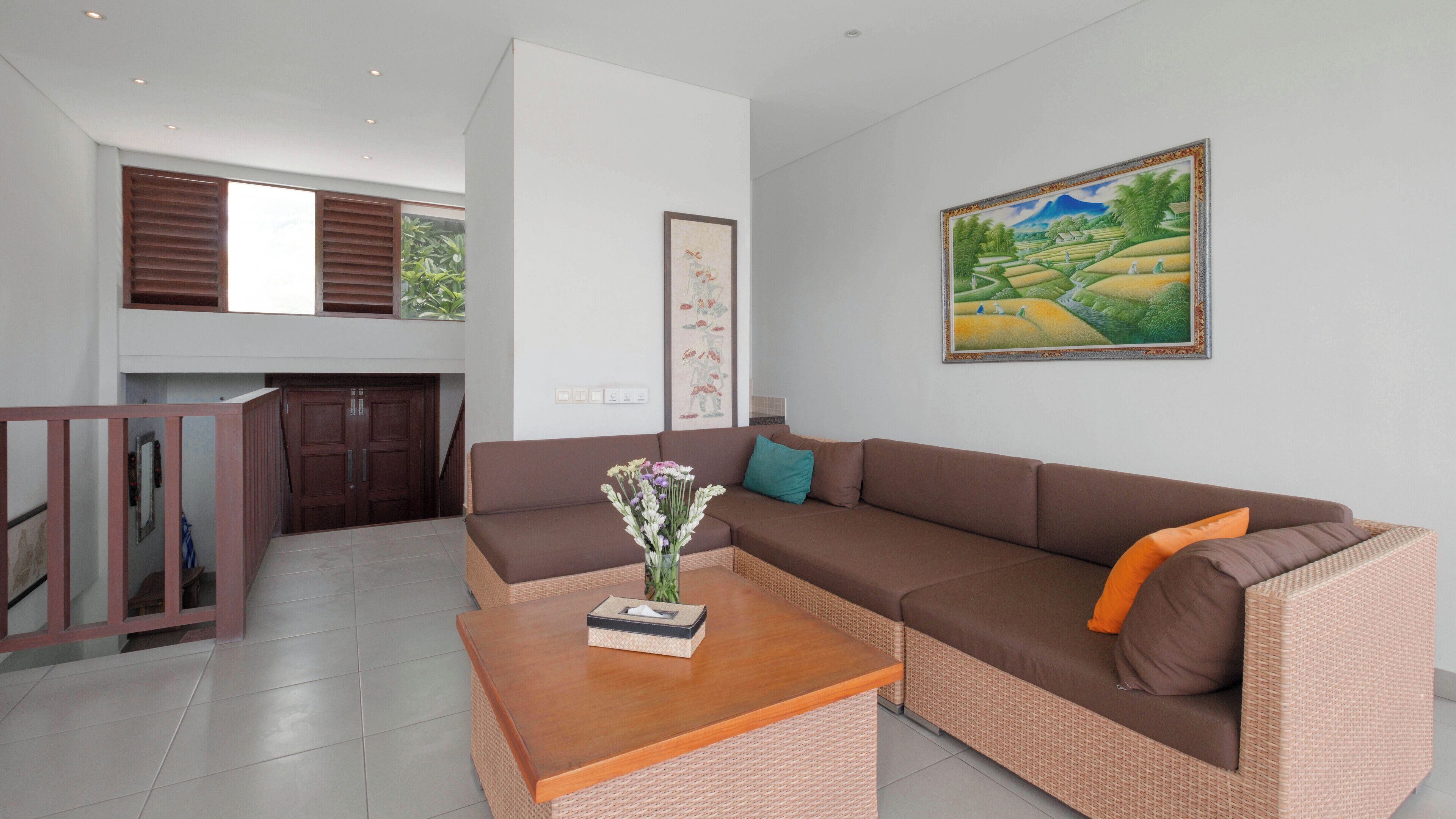 A modern living room with a brown sofa, a wooden coffee table, and a painting of a landscape.