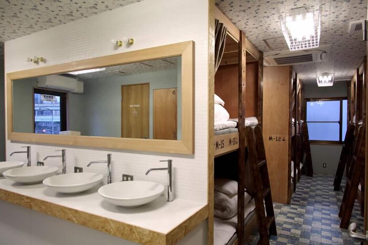 A bathroom with three sinks, a large mirror, and wooden lockers.