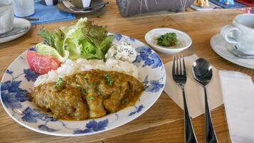 A plate of food with rice, a meat dish, and vegetables on a table with a fork and spoon.