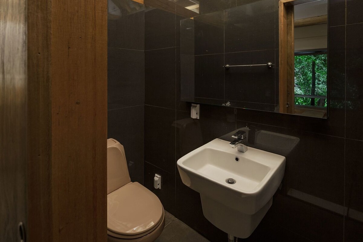 A bathroom with a toilet, sink, and mirror.