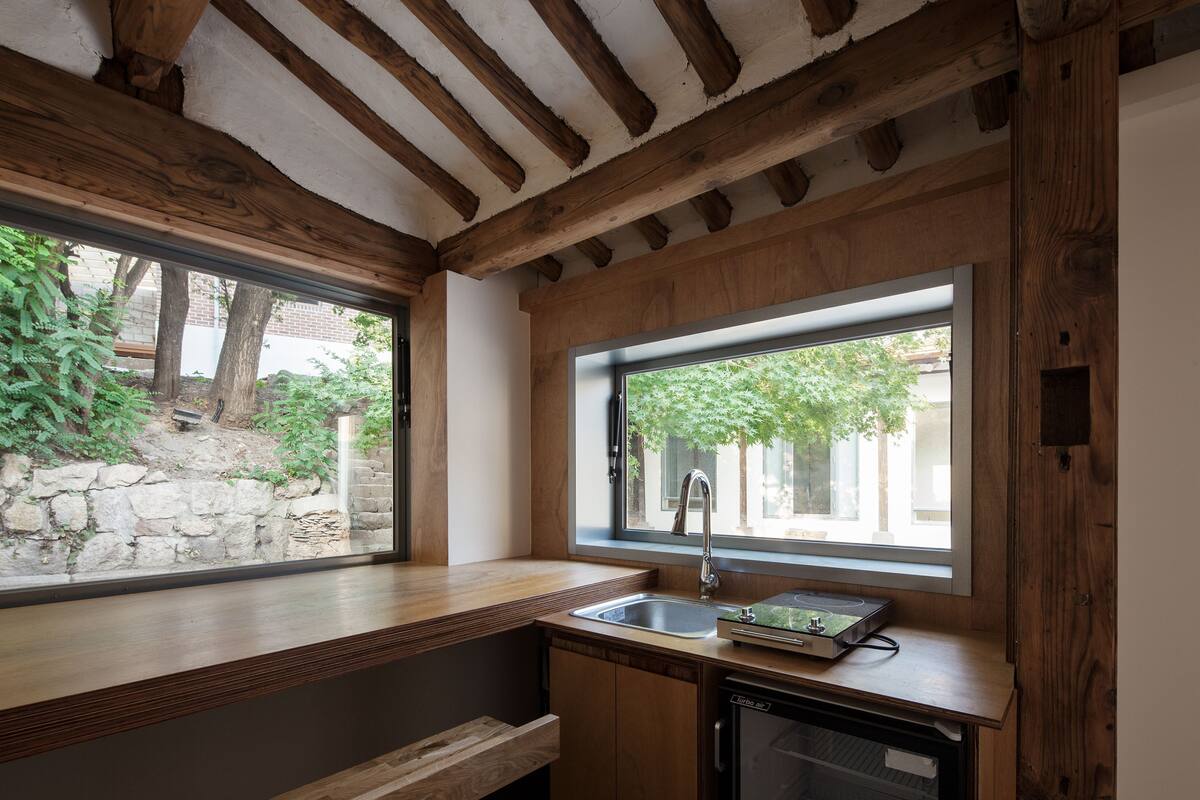 Una cocina con vigas de madera, un ventanal, un fregadero y un lavavajillas.