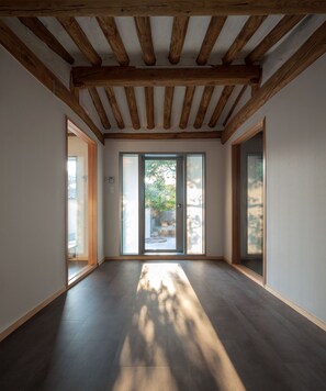 A spacious room with a high ceiling, wooden beams, and large sliding glass doors leading to an outdoor area. - Hanok Residence Hotel Side (Seoul)
