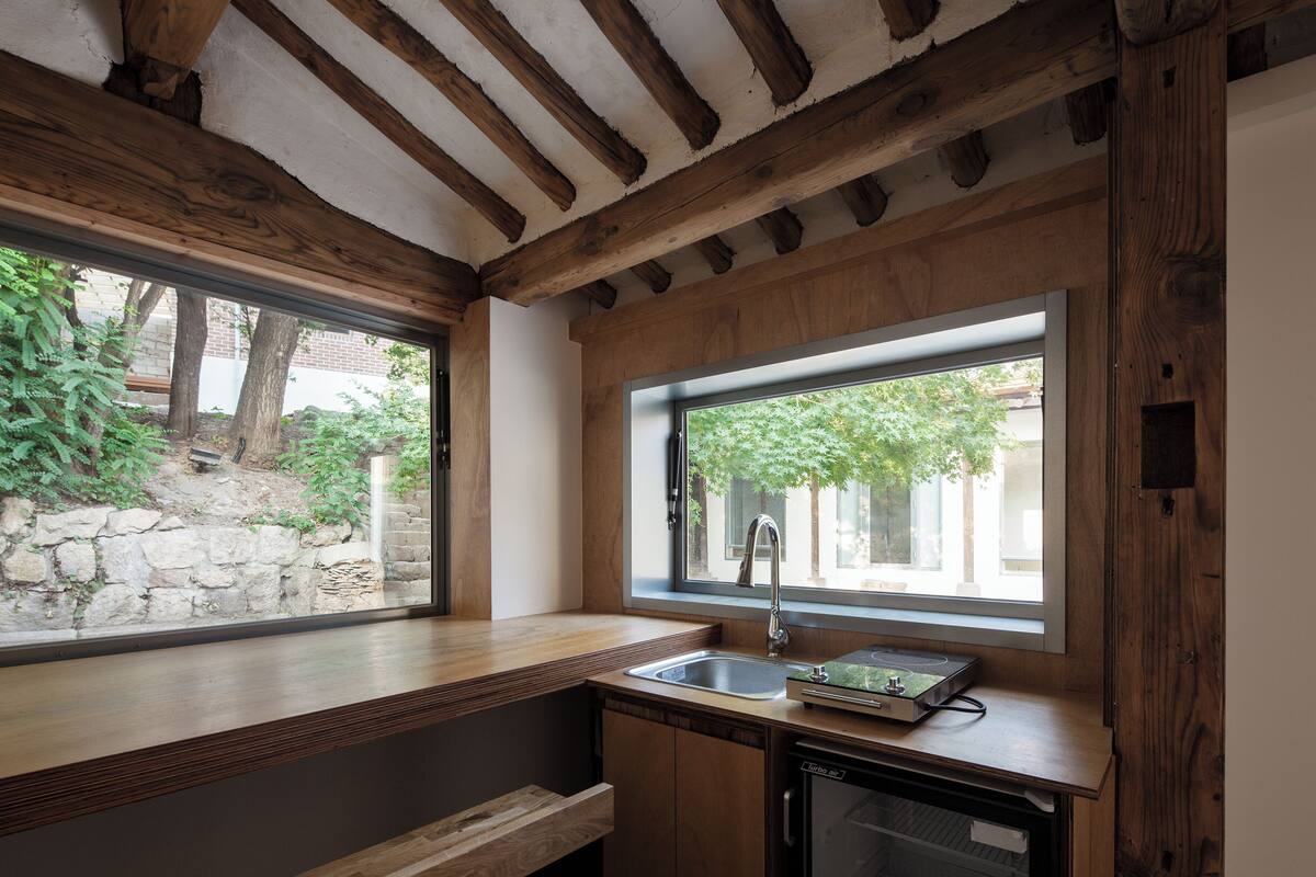 Una cocina compacta con vigas de madera, un lavamanos integrado y lavavajillas.