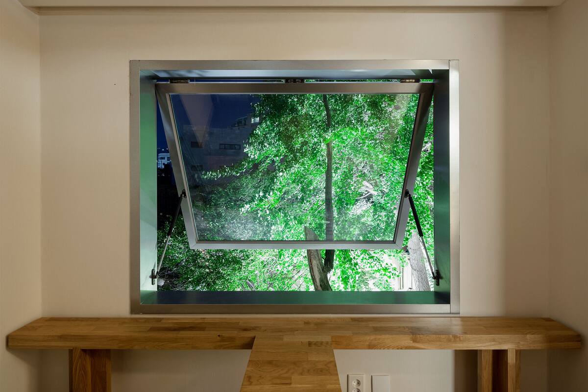 Una habitación con un banco de madera y un ventanal con vistas a un árbol verde.