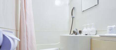 Un baño con inodoro, lavabo, ducha y espejo.