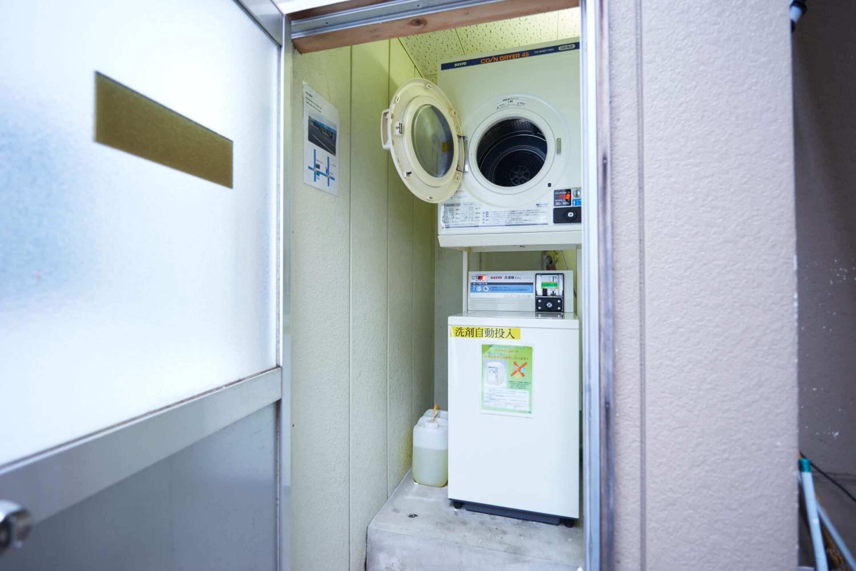 A compact laundry room with a washing machine, a dryer, and a detergent dispenser.