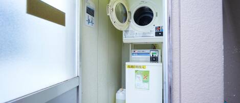 A compact laundry room with a washing machine, a dryer, and a detergent dispenser.