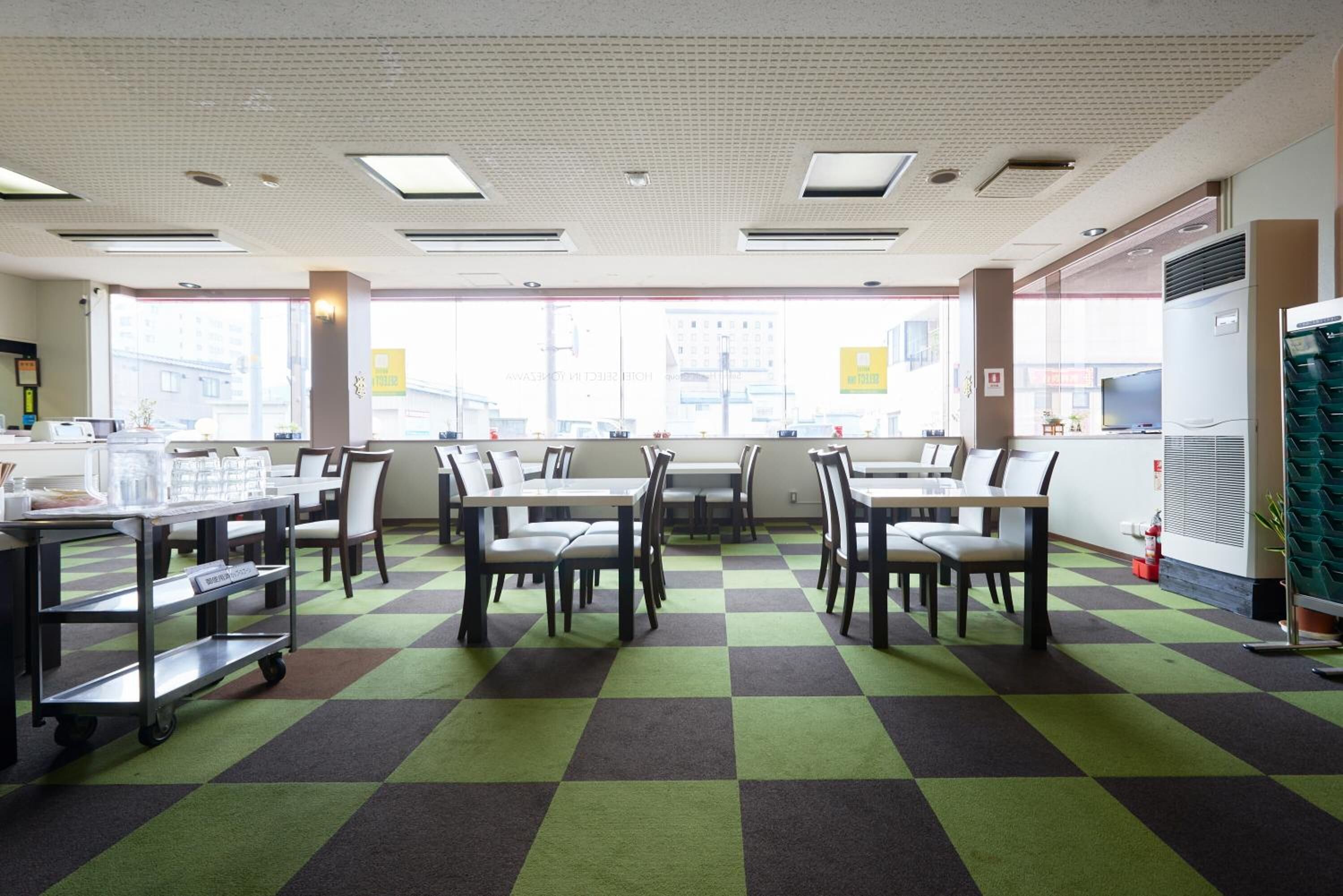 Ein Restaurant mit Schachbrettfußboden, Tischen, Stühlen und Blick auf Gebäude.