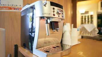Una máquina de café espresso comercial con pantalla digital y panel de control, sobre una encimera de madera con vasos desechables y una bandeja.