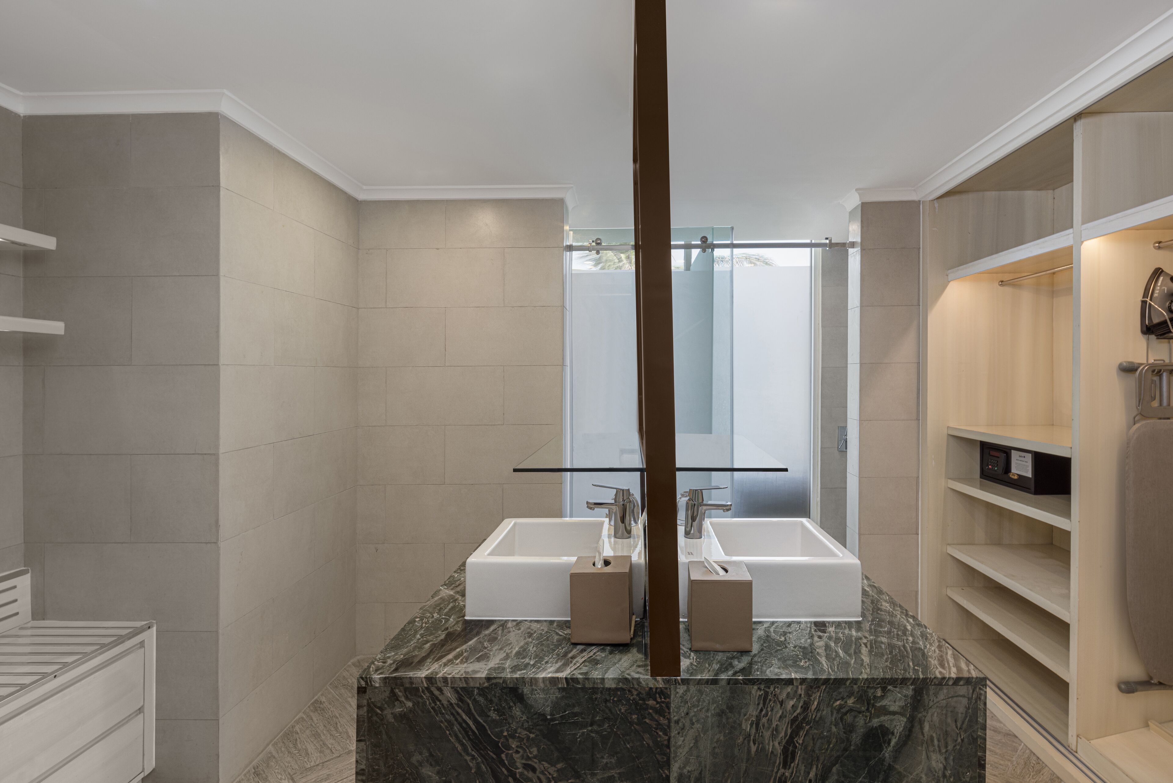Ein modernes Badezimmer mit zwei Waschbecken, einer Duschkabine aus Glas und einer Marmorarbeitsplatte.