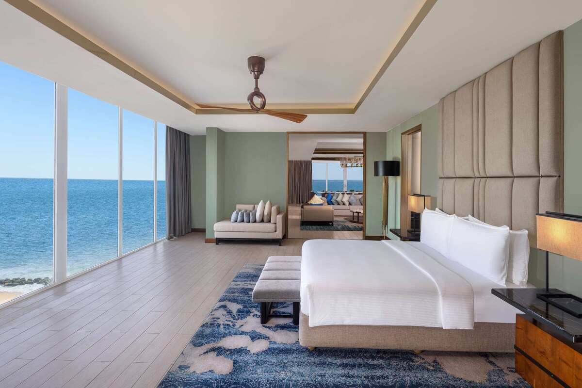 A spacious bedroom with a large bed, a ceiling fan, and a view of the ocean.