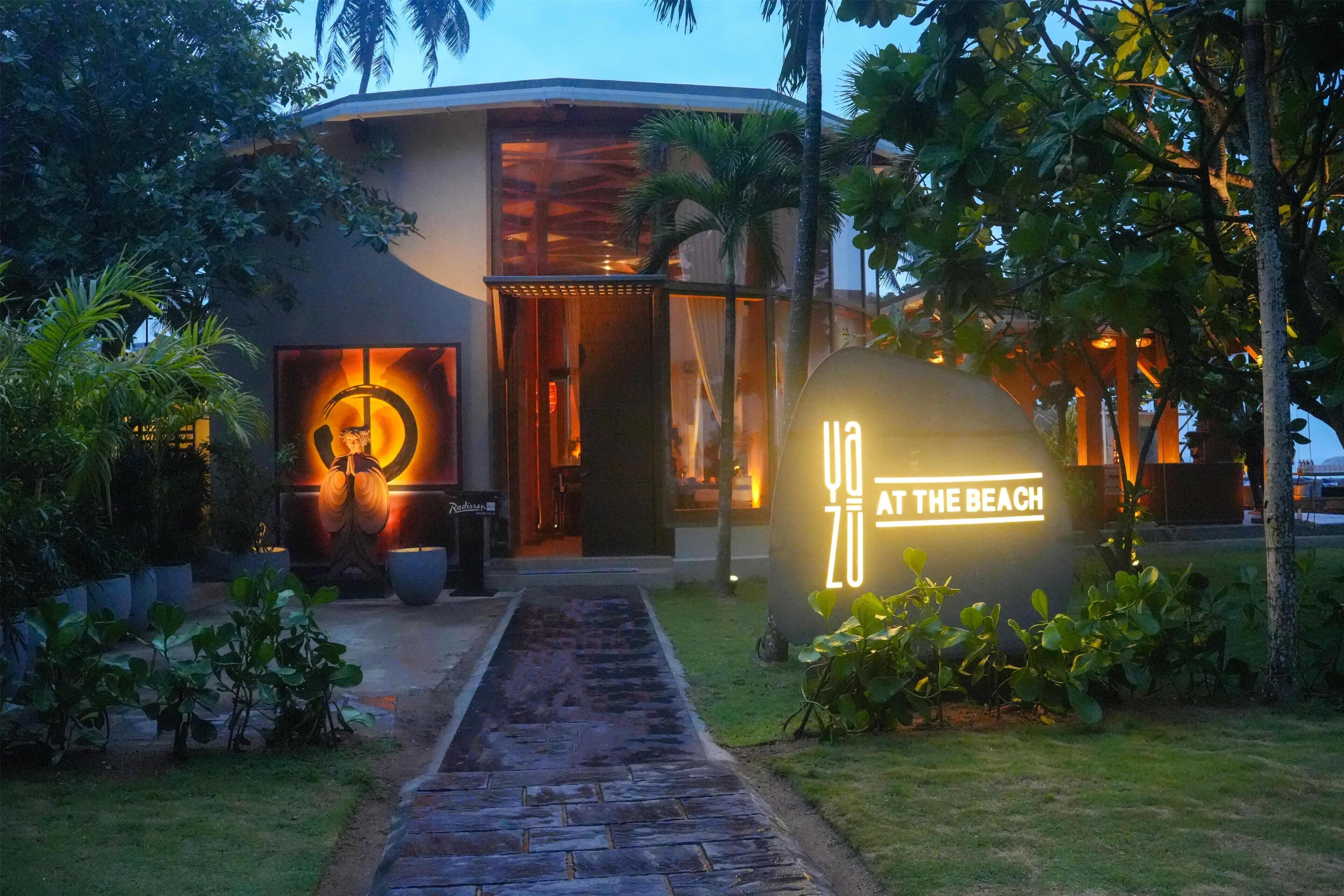 A modern building with a pathway leading to the entrance, surrounded by greenery.