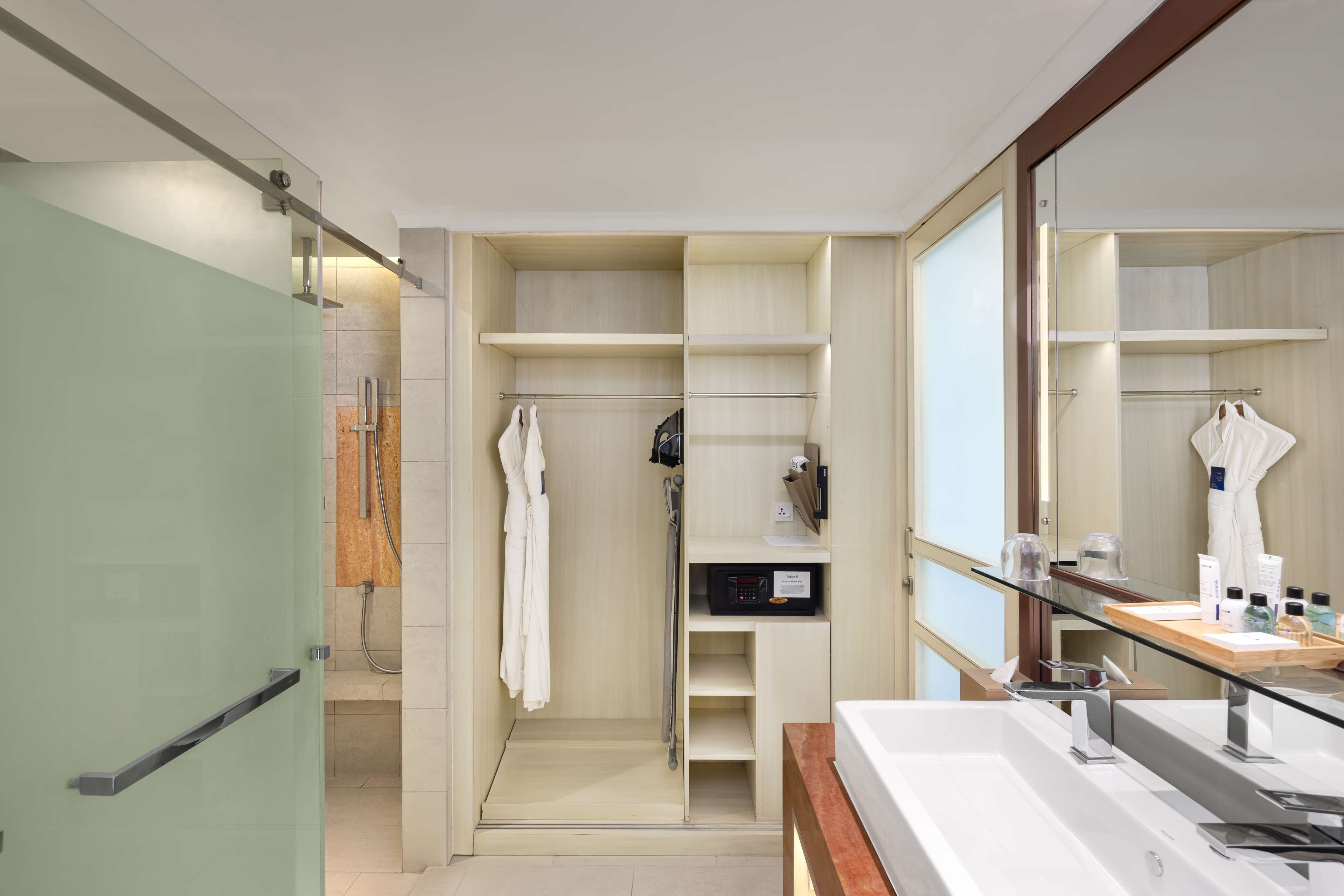 A modern bathroom with a glass shower enclosure, a large mirror, and a vanity with a sink and countertop.
