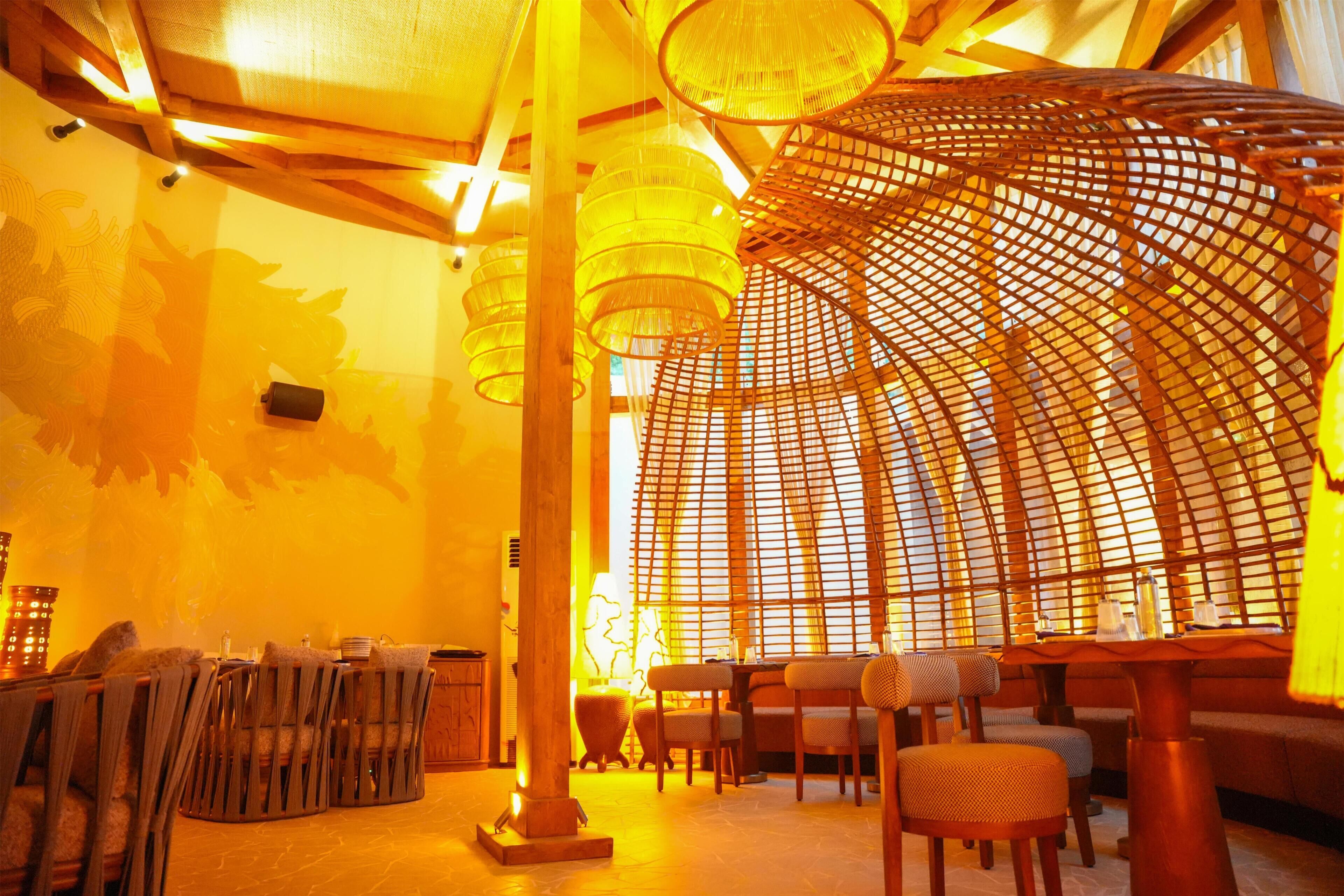 Un restaurante con mobiliario de madera, una columna central y una estructura de techo curva.
